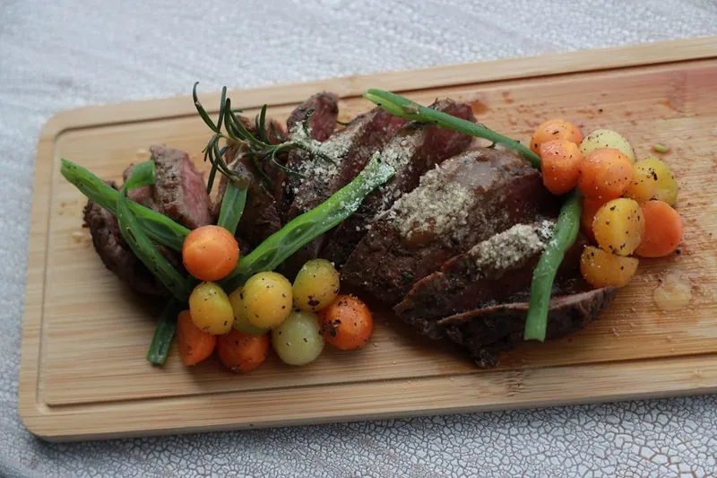 Grilled steak with rosemary and glazed vegetables on a wooden board at The Summit Kandy