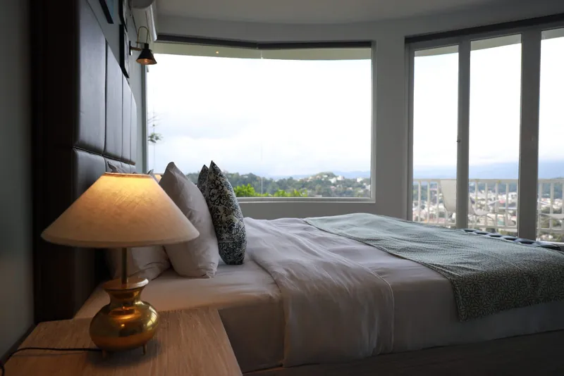 Guest bedroom with a king bed and curved panoramic windows overlooking Kandy at The Summit Kandy