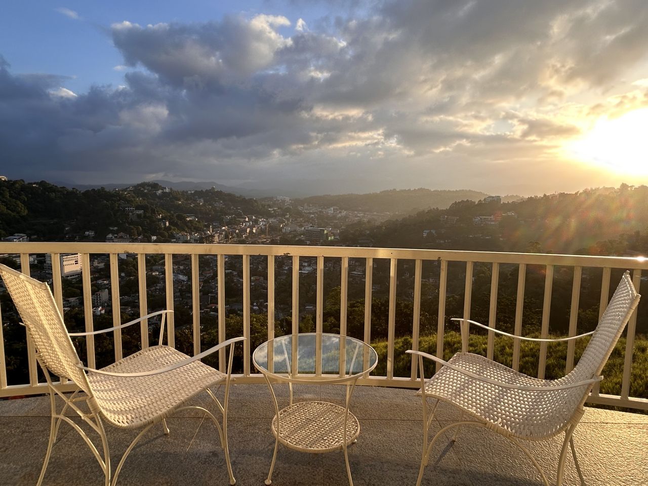 Private balcony with white rattan chairs at sunset overlooking the Kandy hills at The Summit Kandy