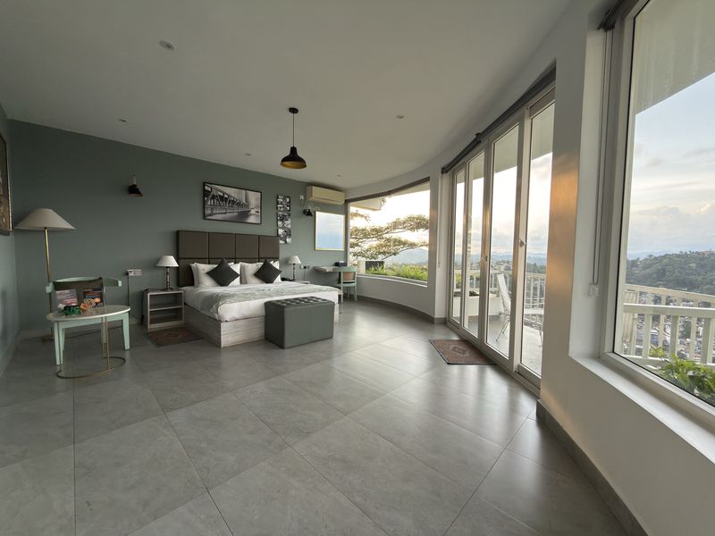 Spacious guest room with a king bed and curved panoramic windows over Kandy at The Summit Kandy