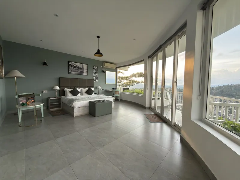 Spacious guest room with a king bed and curved panoramic windows over Kandy at The Summit Kandy