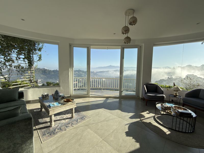 Bright lounge with floor-to-ceiling curved windows and misty hill views at The Summit Kandy