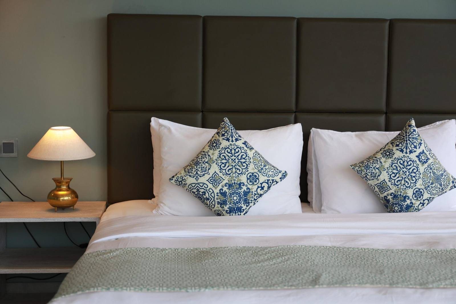 King-size bed with crisp white linen and patterned cushions in a guest room at The Summit Kandy